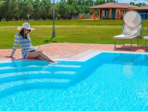 a woman sitting on the edge of a swimming pool at Villa Barbarina - Nature Resort with Pool & Restaurant - Alghero in Santa Maria la Palma