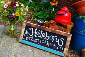 a chalkboard sign with a sign in front of a garden at Eco-Camping De Helleborus, Yurt, Bell & Safari tent, Pipo, Caravans, Dorms and Units in Groningen
