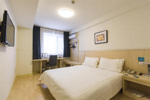 a hotel room with a bed and a desk and a television at Jinjiang Inn Linyi Luozhuang in Linyi