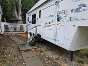 un camper parcheggiato in un cortile con tavolo e sedie di Comfortable RV in a farm a Nanoose Bay 1 altra foto
