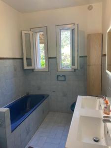 a bathroom with a tub and a sink and two windows at Appartement T2 Alistro San Giuliano Corse in San-Giuliano