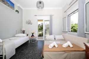 Dos camas en una habitación con paredes y ventanas blancas. en Kaponia's Houses, en Aegina Town
