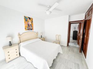 a white bedroom with a bed and a dresser at Apartamento comedia in Sanlúcar de Barrameda
