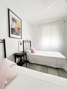 a bedroom with two beds and a table and a window at Apartamento comedia in Sanlúcar de Barrameda