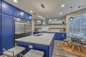 a kitchen with blue cabinets and a kitchen island with chairs at The Woodlands Gem with Pool and Spa in The Woodlands
