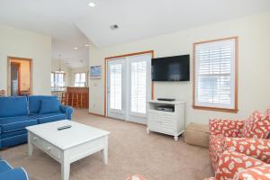 a living room with a blue couch and a tv at Wedges 7 in Nags Head +13 photos