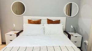 a white bed with white pillows and two mirrors at Exquisite Home & Living in Matsapha