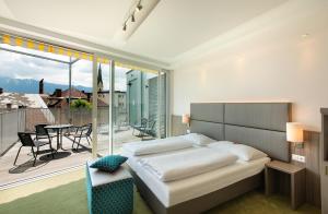 a bedroom with a bed and a balcony with a table at Hotel City in Villach +37 photos