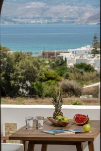 un tavolo in legno con un cesto di frutta e un ananas di Vita Residence ad Agia Anna Naxos