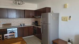 a kitchen with wooden cabinets and a refrigerator at Ferienwohnung mit Meerblick in Khlorakas