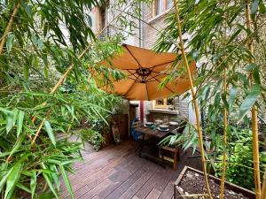 a patio with a table and an umbrella at LE JOSÉPHINE - Havre de paix proche Paris in Montreuil