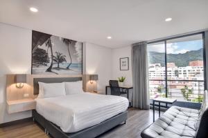 a bedroom with a bed and a couch and a window at Loft Home Suites 118 By gA in Bogotá