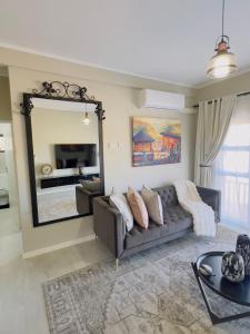 een woonkamer met een bank en een grote spiegel bij LLL Apartments M6 in Khakalashwe