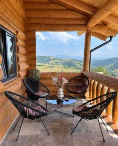 a patio with chairs and a table on a porch at Sub Stele Chalets in Holbav