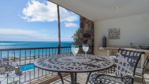 a table with two wine glasses on a balcony with the ocean at The Great Escape Modern Oceanfront in Puerto Peñasco