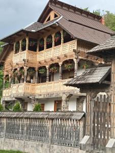 a wooden house with a balcony and a fence at Casa Boris in Bîrsana
