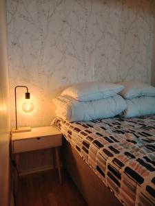 a bed with pillows and a lamp on a night stand at Studio in Joensuu in Joensuu