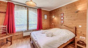 a bedroom with wooden walls and a bed with red curtains at Résidence Les Soldanelles - Chalets pour 10 Personnes MAE-2760 in Champagny-en-Vanoise