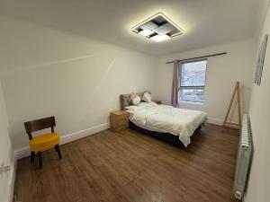 a bedroom with a bed and a chair and a window at Wellesley Apartments in Great Clacton