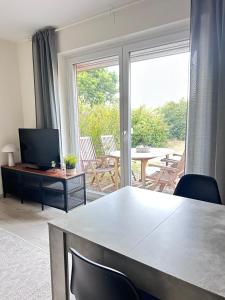 a living room with a table and a television and a patio at Bude in Burgwedel - frisch saniert in 2025 NEW NEW in Burgwedel