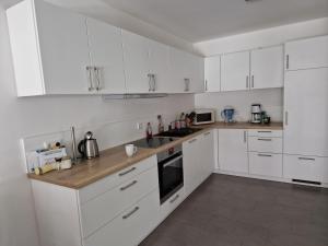 a white kitchen with white cabinets and appliances at Ama - viel Platz, großer Balkon, barrierearm in Bad Kissingen +7 photos