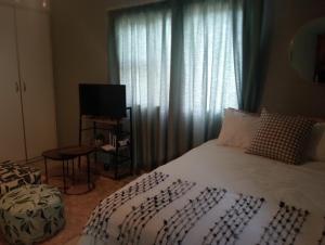 ein Schlafzimmer mit einem Bett und einem Fenster mit Fernseher in der Unterkunft Lee Crib in Empangeni