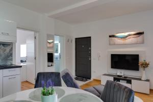 a living room with a table and chairs and a television at Lemona Apartmani Vrnjačka Banja in Vrnjci