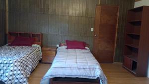 a bedroom with two beds and a book shelf at Habitaciones Alpinas Oxapampa in San Antonio