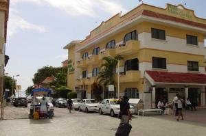 un grand bâtiment jaune avec des voitures garées devant dans l'établissement Hotel Vista Caribe Playa, à Playa del Carmen 9 autres photos