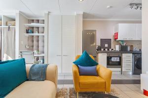 una sala de estar con un sofá y una silla en The Paddocks Pearl -115, en Fourways