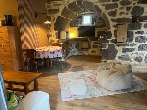 a living room with a table and a stone wall at La maison des petites choses, la tiny house du Puy Mary-Cantal in Lascelle