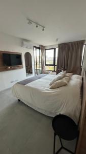 a bedroom with a large bed with a chair and a tv at Brickell Aiby in Tigre +18 photos