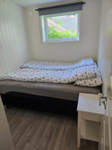 a bed in a small room with a window at Barnevennlig leilighet nær båthavn og sentrum in Tromsø