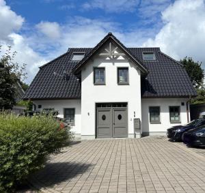 a white house with a black roof and a driveway at Zum Schwedenblick in Zingst