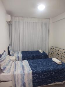a bedroom with two beds and a table and a window at Apartamento no Paraíso dos Corais com Vista Mar in Camacari