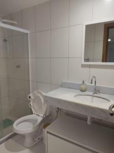 a bathroom with a toilet and a sink and a mirror at Apartamento no Paraíso dos Corais com Vista Mar in Camacari