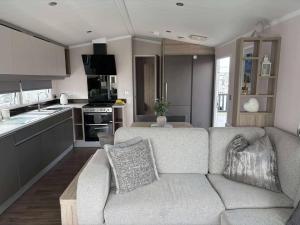 a living room with a couch and a kitchen at The Retreat Sea Breeze - Golden Sands Holiday Park in Kinmel Bay