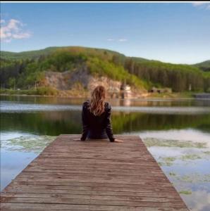 ノヴァ・ヴァロシュにあるBrvnara Uvac ZLATARの湖の桟橋に腰掛けた女