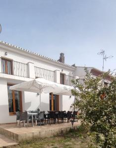 une maison blanche avec une table, des chaises et un parasol dans l'établissement Casa El Molino de Melegis - Lecrin Valley, à Melegis