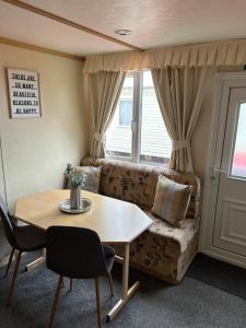 a living room with a table and a couch at Bailey's Caravan Hire - Sealands Plot 1 - Wi-Fi - Dog Friendly in Ingoldmells