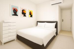 特拉维夫Private rooms near the beach center的白色卧室配有一张床,墙上挂有绘画作品