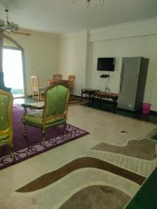 Una sala de estar con sillas, una mesa y un televisor. en شقه فيو بحر ميامي مكيفه, en Alejandría