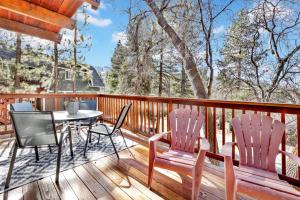 eine Holzterrasse mit einem Tisch und Stühlen darauf in der Unterkunft Chipmunk treehouse #1983 in Big Bear Lake