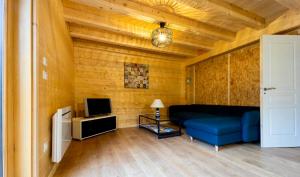 un salon avec un canapé bleu et une télévision dans l'établissement Le Nine CHALET COSY - NATURE, LAC, MONTAGNES & GOLF, à Giez