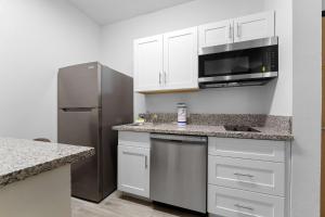 a kitchen with white cabinets and a stainless steel refrigerator at Metro Extended Stays , Chandler - Cozy 2 Beds in Chandler