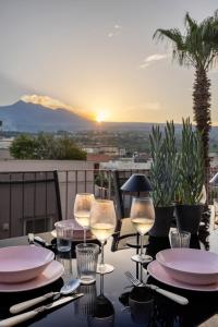 a table with plates and wine glasses on a balcony at Luxury Panoramic Loft with heated saltwater pool and parking near Taormina, Catania, the Sea and Mount Etna by SicilianRelaxingHomes in Giarre