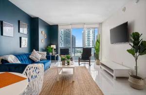 a living room with a blue couch and a tv at Modern Icon Brickell Condo by Palermo Home Miami in Miami