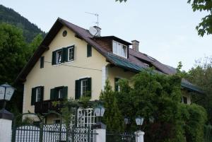 a white house with green shutters and a fence at Seevilla Annenheim in Annenheim