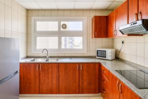 a kitchen with wooden cabinets and a sink and a window at Ruwi Hotel Apartments, Sharjah in Sharjah