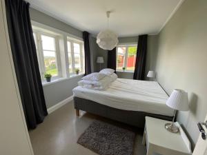 a small bedroom with a bed and two windows at Nära centrum med sjöutsikt -Korsgården in Rättvik